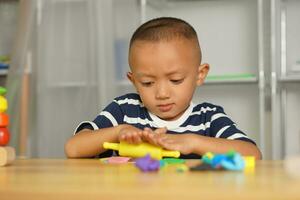 een jongen kneedt plasticine naar maken dingen zacht. foto