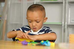 een jongen kneedt plasticine naar maken dingen zacht. foto