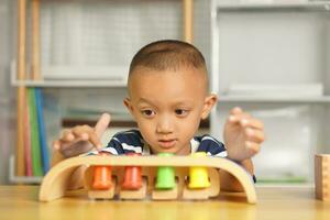 een jongen Toneelstukken met ontwikkelingsstoornissen speelgoed Aan de tafel binnen de huis. foto