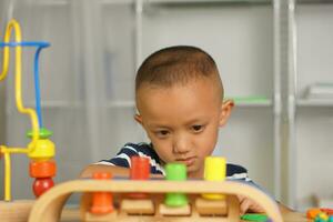een jongen Toneelstukken met ontwikkelingsstoornissen speelgoed Aan de tafel binnen de huis. foto