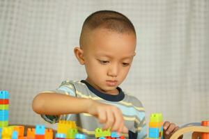 Aziatisch jongen spelen met leerzaam speelgoed Daar zijn veel mooi kleuren Aan de tafel in de huis. foto