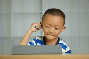 een jongen horloges een les Aan een portable computer. foto