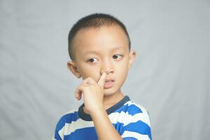 Aziatisch jongen stokjes vinger in neus- foto