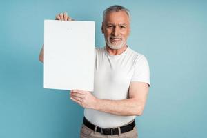 lachende gepensioneerde met een baard die een blanco vel papier vasthoudt foto