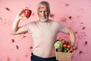 glimlachend, oudere man houdt een mand met groenten vast foto