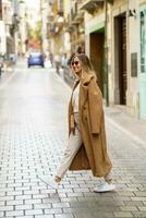elegant vrouw in jas kruispunt straat foto