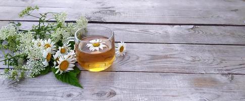 kamille aromatische thee in een glazen beker op een houten ondergrond foto