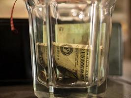 een dollar en munten in een glazen facet geslepen glas