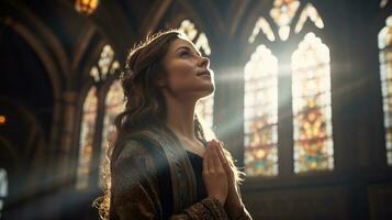 een jong vrouw is zittend binnen een kerk en verschijnt naar worden diep in gebed. foto