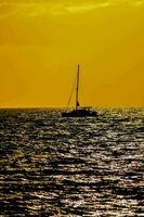 een zeilboot is gezien in de afstand Bij zonsondergang foto