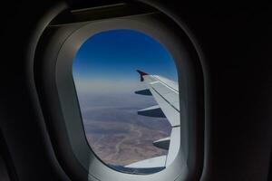 visie door de venster van een vliegtuig gedurende een vlucht over- de woestijn foto