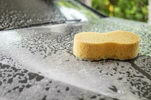auto schoonmaak en het wassen met geel spons en schuim zeep foto