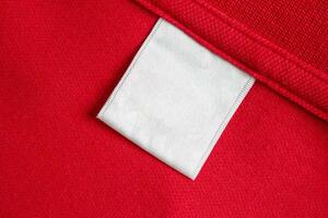 blanco wit wasserij zorg kleren etiket Aan rood overhemd kleding stof structuur achtergrond foto