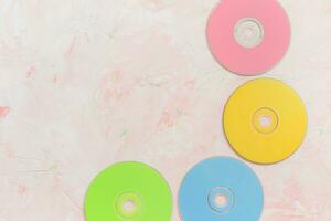 kleurrijk CD of DVD schijven Aan roze. retro minimalistische achtergrond, 80s tendens, kopiëren ruimte foto