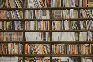 industrieel donker houten boekenkasten gevulde met sociaal, fictie, zelf verbetering en biografie boeken in een openbaar bibliotheek of een boekhandelaar winkel. yogakarta, Indonesië - 08 28 2023 foto