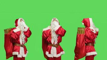 moe heilige Nick geeuwen Aan groene scherm achtergrond, gevoel uitgeput van draag- zak met cadeaus en speelgoed voor Kerstmis vooravond vakantie. de kerstman claus belichaming gevoel slaperig in studio, rood pak. foto