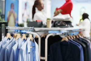 formeel overhemden en jassen hangende Aan Scherm rek presentatie van laatste aankomst handelswaar in kleinhandel boodschappen doen winkelcentrum met wazig achtergrond. kleding Aan hangers in mode winkel dichtbij omhoog foto