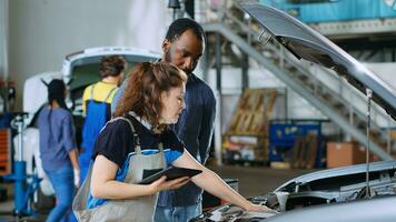 monteur in auto onderhoud toepassingen tablet naar berekenen reparaties factuur voor cliënt na vaststelling gebroken componenten. auto reparatie winkel arbeider toepassingen apparaat naar informeren Mens van laatste kosten na repareren voertuig foto