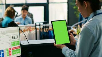 Aziatisch op te slaan arbeider op zoek Bij chroma sleutel groen scherm bespotten omhoog tablet computer met kopiëren ruimte Scherm in boodschappen doen winkelcentrum. manager staand Bij teller bureau in modern boetiek. mode concept foto