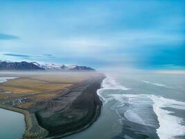 atlantisch kust zwart zand strand met enorm golven crashen Aan IJslands kustlijn, majestueus natuurlijk instelling waar oceaan voldoet aan de strand in IJsland. antenne visie van prachtig landschap. foto