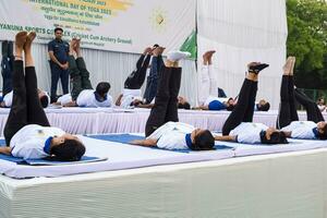 nieuw Delhi, Indië, juni 21, 2023 - groep yoga oefening sessie voor mensen Bij Yamuna sport- complex in Delhi Aan Internationale yoga dag, groot groep van volwassenen Bijwonen yoga klasse in krekel stadion foto