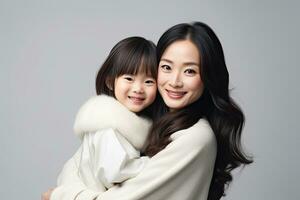 portret van een gelukkig Aziatisch moeder en dochter poseren in studio, vrolijk Aziatisch kleuter dochter knuffelen gelukkig moeder geïsoleerd Aan grijs, ai gegenereerd foto