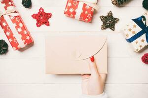 top visie van vrouw hand- Holding een envelop Aan houten achtergrond. nieuw jaar decoraties. Kerstmis tijd concept foto