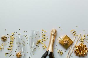 fles van Champagne met gekleurde schitteren, confetti en geschenk doos ruimte voor tekst Aan kleurrijk achtergrond, top visie. hilarisch, Kerstmis en verjaardag viering foto