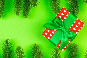 top visie van Spar boom takken en geschenk doos Aan kleurrijk achtergrond. Kerstmis tijd concept met leeg ruimte voor uw ontwerp foto