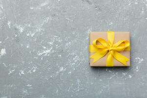 vakantie geschenk doos verpakt in ambacht papier met gekleurde boog Aan tafel achtergrond. top visie, vlak leggen, kopiëren ruimte foto