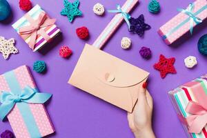 top visie van vrouw Holding een envelop Aan Purper achtergrond gemaakt van vakantie decoraties. Kerstmis tijd concept foto