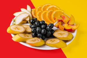 bord met verschillend fruit Aan geel en rood achtergrond foto
