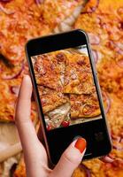 vrouw hand- maken een foto van pizza met een mobiel telefoon