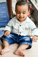 baby jongen Bij huis balkon. helder portret van gelukkig kind zittend Aan de tafel. weinig 1 jaar oud jongen gedurende de dag licht Bij huis balkon. foto