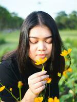 portret van tuinman jong vrouw Aziatisch mollig schattig mooi een persoon op zoek hand- Holding zorgzaam voor planten bladeren tuin park schoonheid bloemen avond zonlicht vers glimlachen gelukkig kom tot rust zomer dag foto