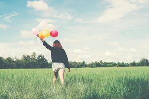achterkant van gelukkige jonge vrouw die op het groene veld staat, geniet met frisse lucht foto