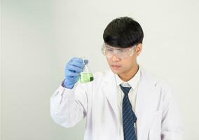 Aziatisch Mens leerling wetenschapper of dokter kijken hand- Holding in reagens menging laboratorium in een wetenschap Onderzoek laboratorium met test buizen van divers maten in laboratorium chemie laboratorium wit achtergrond. foto