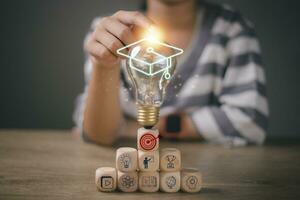 handen aanraken licht lamp met diploma uitreiking hoed Aan houten kubussen gestapeld, internet onderwijs Cursus rang, e-learning afstuderen certificaat programma concept. studie kennis naar creatief denken ideeën. foto