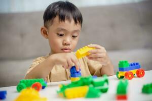 de kind spelen met kleurrijk speelgoed- blokken. weinig jongen gebouw de auto van blok speelgoed. leerzaam en creatief speelgoed en spellen voor jong kinderen. foto