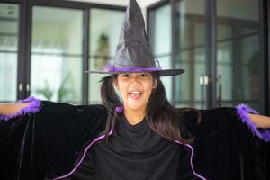 gelukkig Aziatisch kind meisje in een heks kostuum naar halloween. truc of traktatie. kinderen truc of behandelen. foto