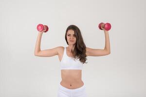 portret van jonge mooie vrouw die fysieke oefeningen met dumbbells maakt foto