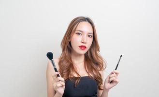 portret mooie Aziatische vrouw met make-up borstel op witte achtergrond foto