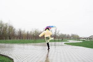 vrouw met kleurrijke paraplu wandelen in de regen, van achteren bekijken foto