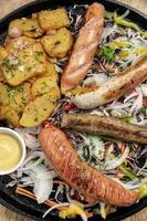 gemengde Duitse traditionele biologische worst en aardappelschotel inclusief nurnberger, lams- en varkensvlees met salade en mosterd foto
