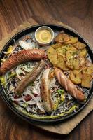 gemengde Duitse traditionele biologische worst en aardappelschotel inclusief nurnberger, lams- en varkensvlees met salade en mosterd foto
