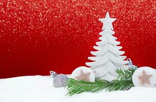 wit glimmend Kerstmis boom met zilver ballen en sterren met pijnboom Afdeling Aan sneeuw Aan kant, achter fonkeling rood achtergrond. nieuw jaar. kopiëren ruimte foto