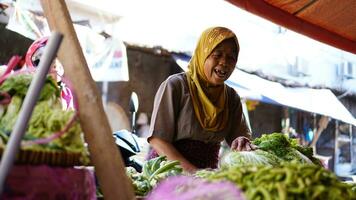 groente verkoper moslim Indonesië Dames met hoofddoek is portie klanten in de markt. boodschappen verkoper. verkoper Dames in de traditioneel markt foto