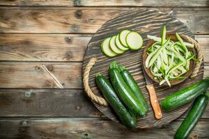 stukken van courgette in een kom Aan een snijdend bord met een mes. foto