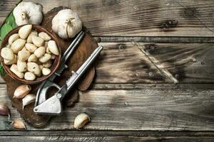 kruidnagel van vers knoflook Aan een snijdend bord met een knoflook druk op. foto