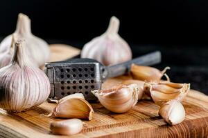 kruidnagel van knoflook Aan een snijdend bord met een knoflook druk op. foto